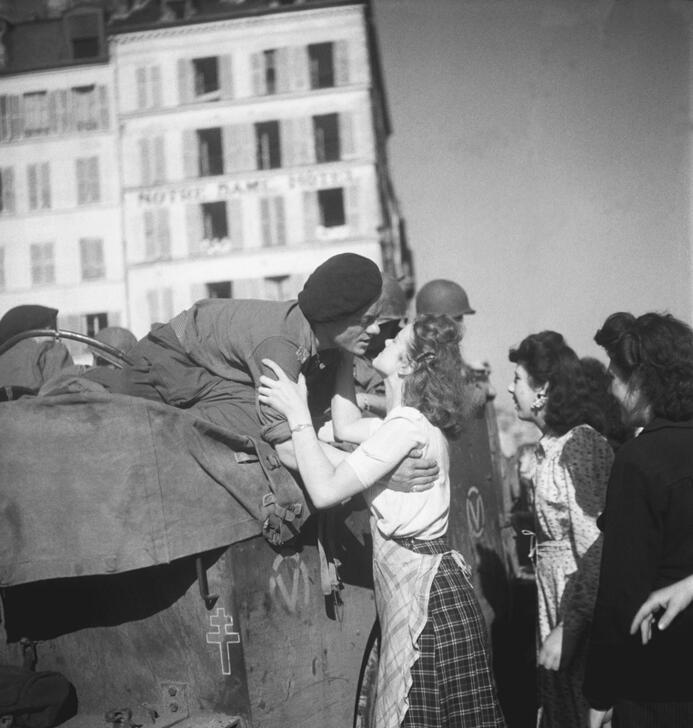 A young woman kisses a soldier from General Leclerc's 2nd Armoured Division as he leans towards her from his military vehicle on the Quai Montebello. Behind her, the Notre-Dame Hôtel, on the corner of Place du Petit-Pont. AKG10780382 © René Zuber / akg-images
