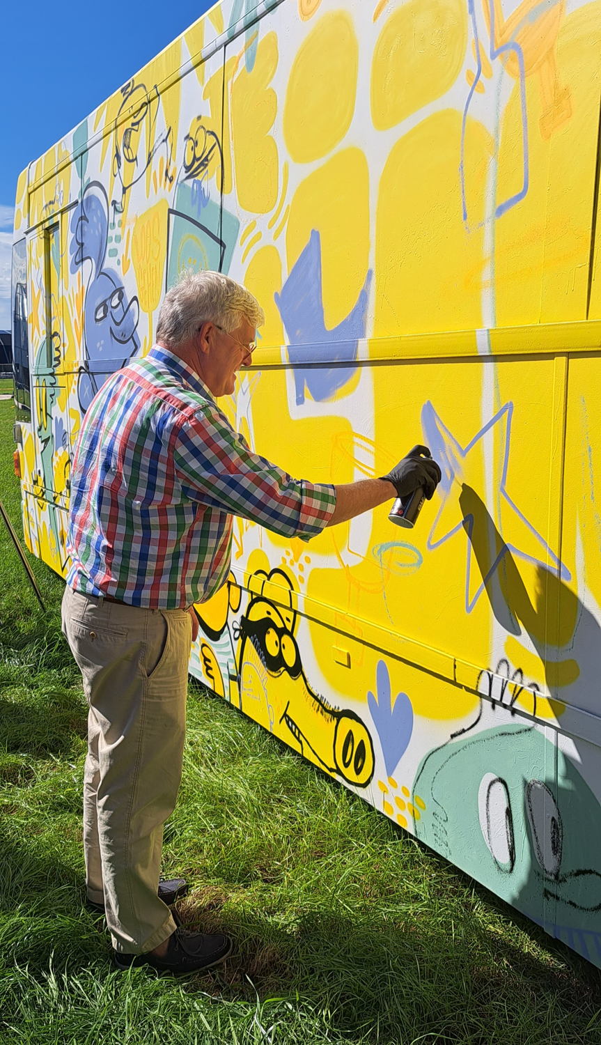 Gedeputeerde Lambrechts voegt zijn creatie toe aan de speciale Pukkelpop-bus van De Lijn.