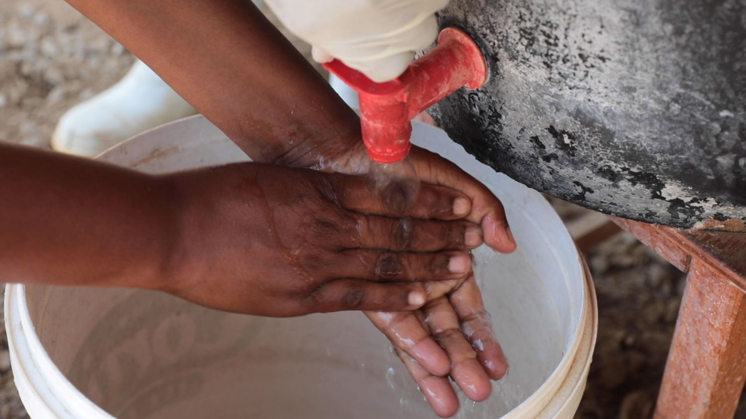 A suspected cholera patient washes hands for infection control purposes at the Glenview Cholera Treatment Centre, Harare. As part of the current cholera response in Harare, MSF mentored nurses to manage patients and sprayers for infection control. Infection control is an important aspect of preventing the spread of cholera. Photographer: Marion Mossing