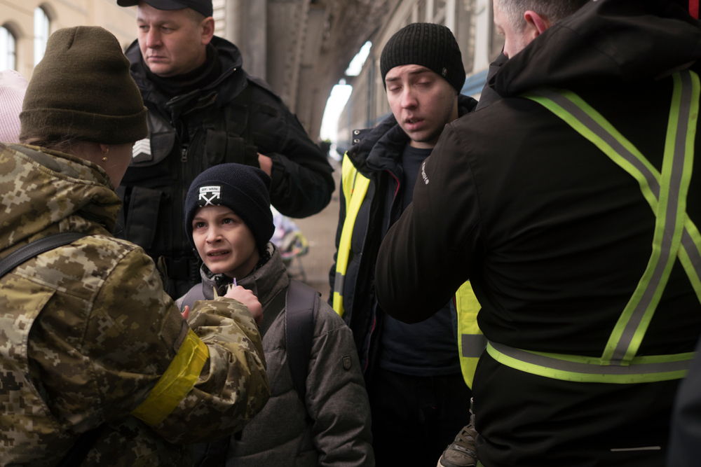 Un petit garçon écoute, inquiet, les admonitions d'une femme agent de la gare de Lviv en Ukraine. ​ Photo, 1er mars 2022 ​ © Emmanuel Ortiz / akg-images