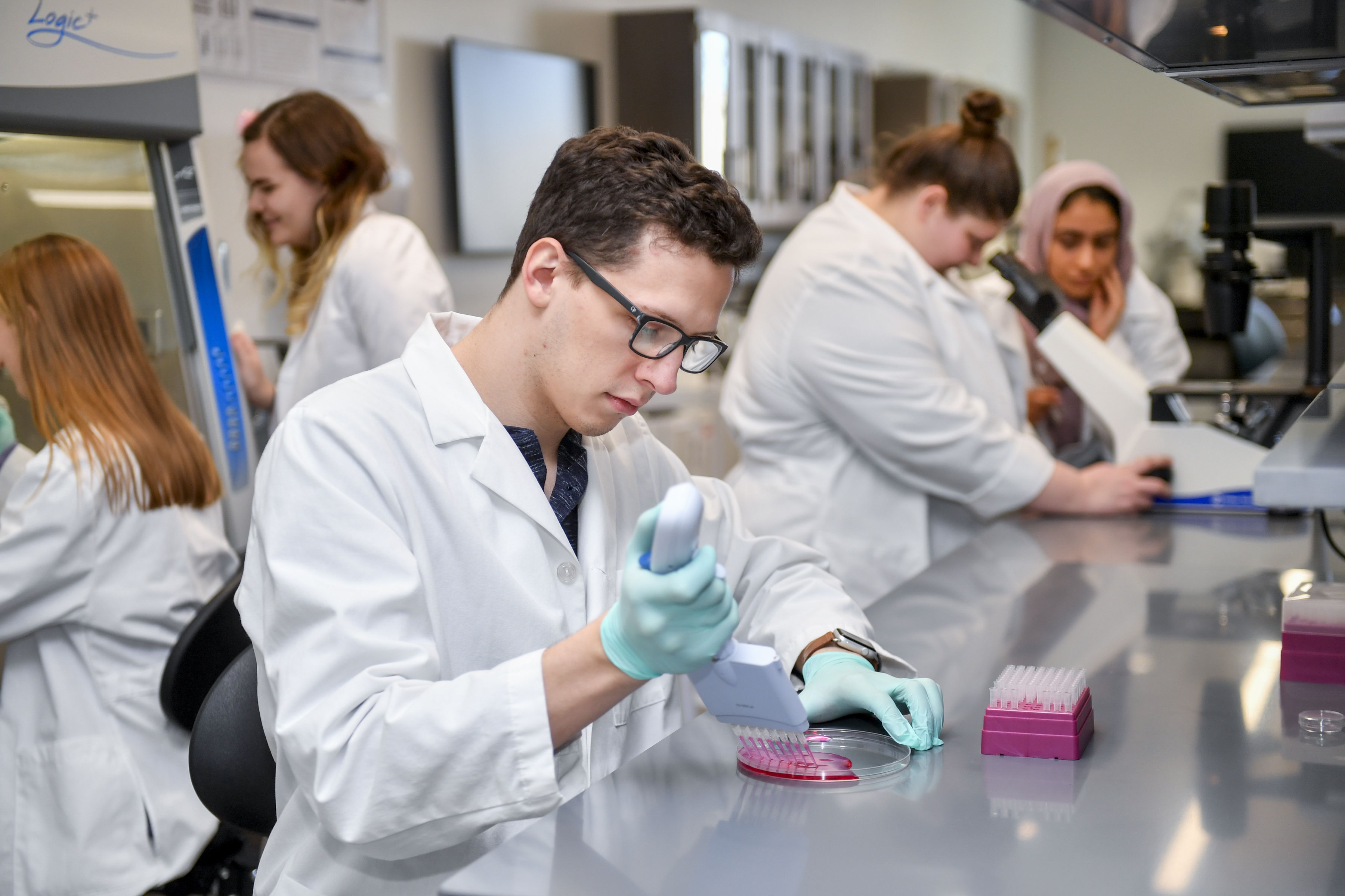 A UCO student in a lab coat works in a lab.