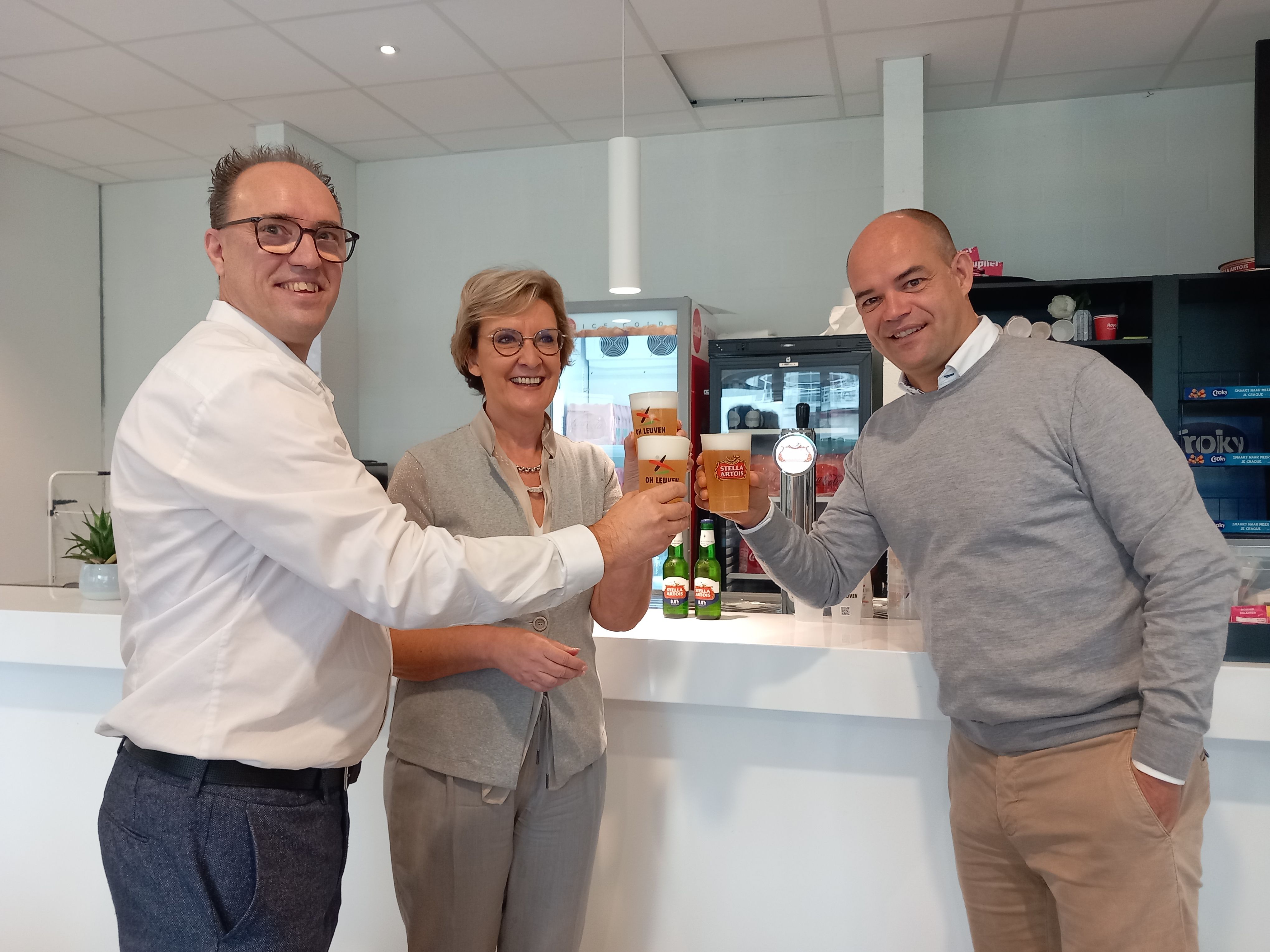 Olivier Bernard van AMAB, gedeputeerde Ann Schevenels en Peter Willems, CEO van OH Leuven, nemen de eerste herbruikbare bekers in het stadion van OH Leuven in gebruik.