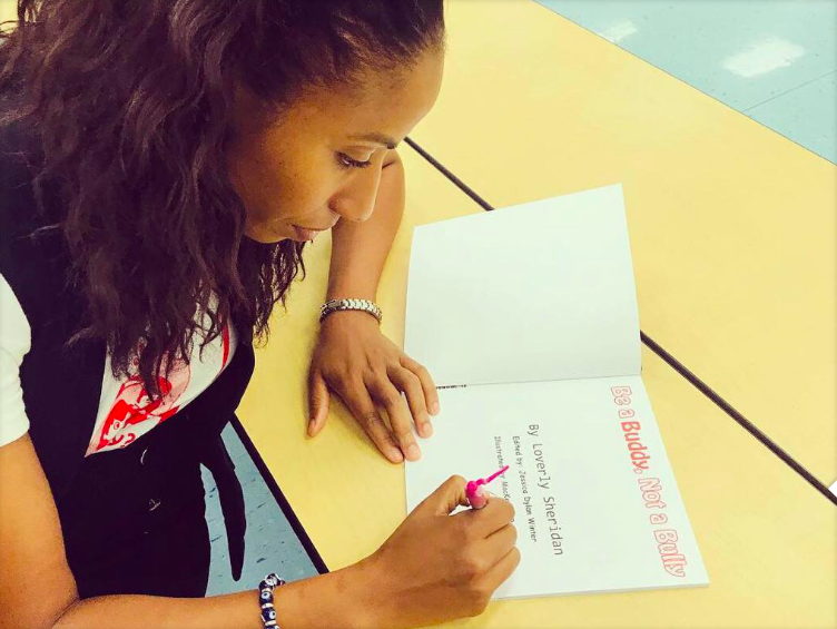 Sheridan signs a copy of her book "Be a Buddy, Not a Bully"
