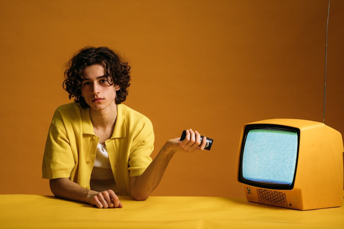 Free Young man in yellow with a vintage TV in a cool, retro setting. Stock Photo