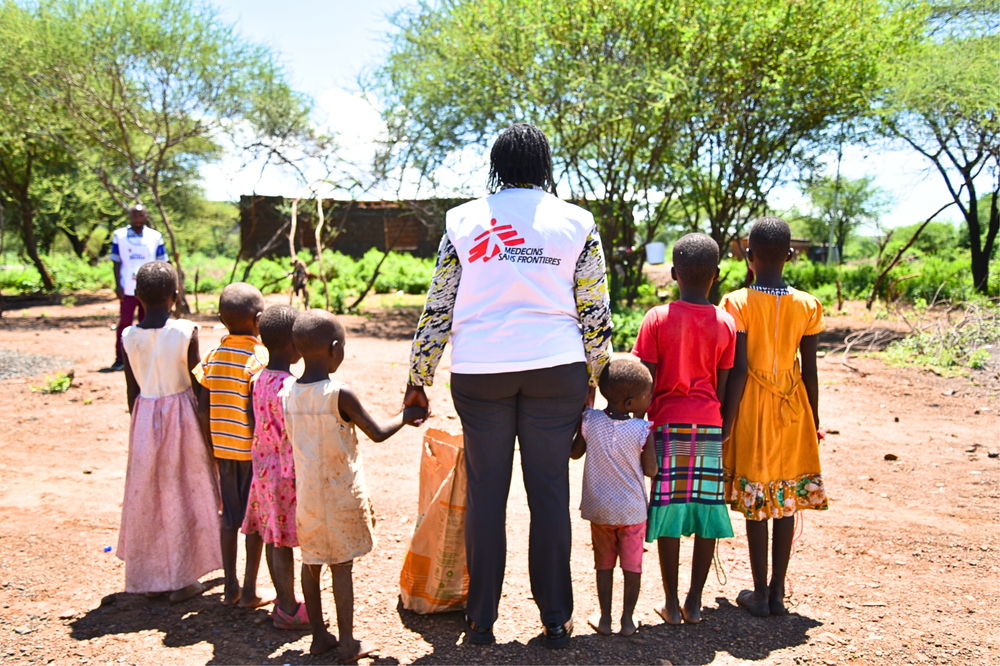 :Nancy Mutai, a psychologist (centre), poses for a photo with children at the Moinonin camp in Baringo county. Photographer: Zainab Mohammed |Location: Kenya |Date: 06/05/2024