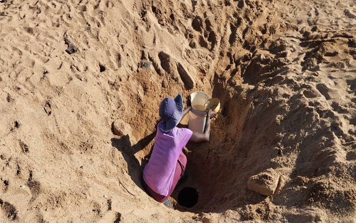 A woman fetching drinking water in dug hole in the salted river in Buhera | Photographer: Grace Mavezha | Date: 02 May 2024
