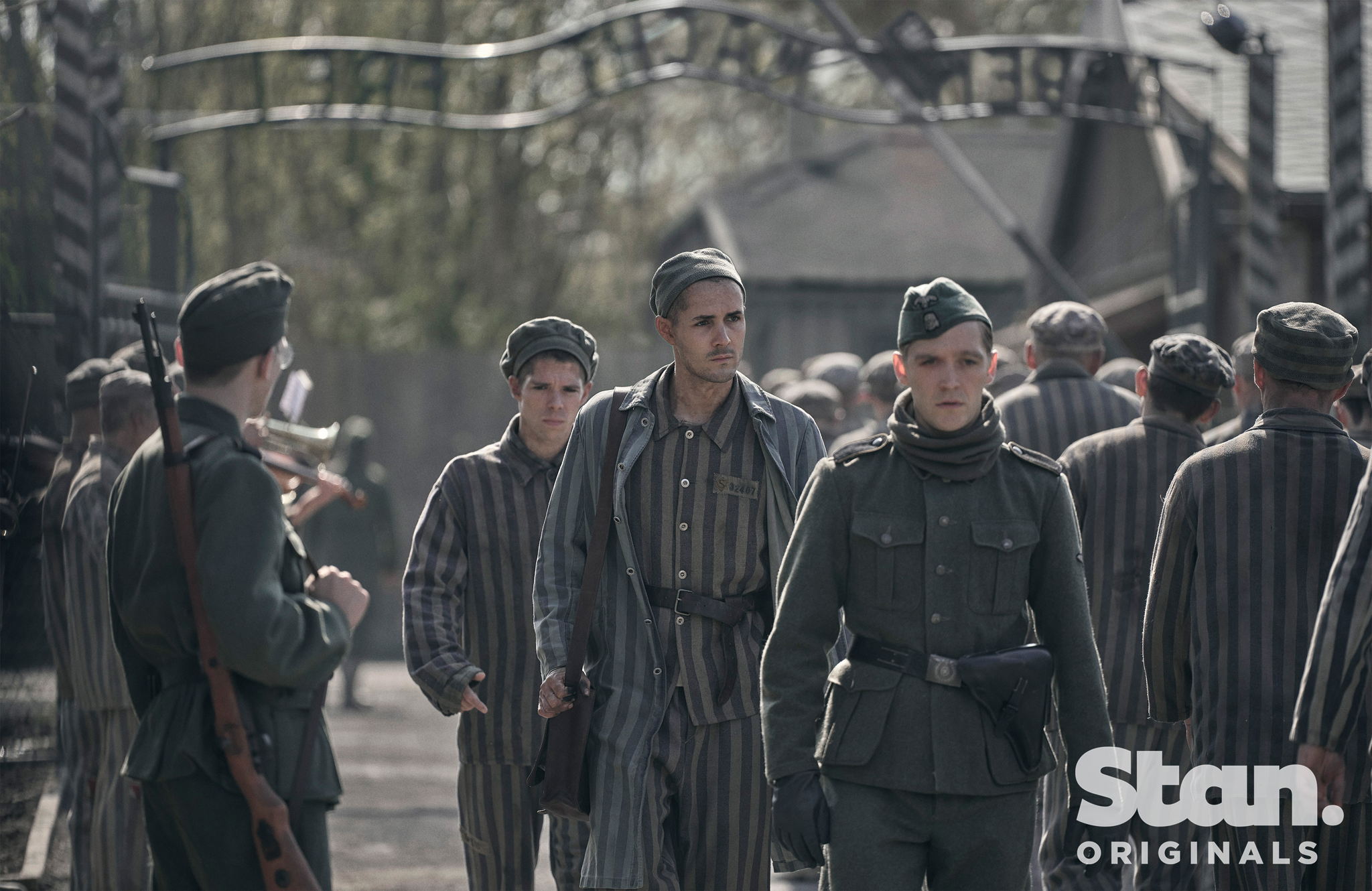 Caption: Jonah Hauer-King as Lali Sokolov seen here walking through Auschwitz with German-born actor Jonas Nay as Nazi officer Stefan Baretzki, front right (Credit: © Martin Mlaka / Sky UK) Caption: Jonah Hauer-King as Lali Sokolov seen here walking through Auschwitz with German-born actor Jonas Nay as Nazi officer Stefan Baretzki, front right (Credit: © Martin Mlaka / Sky UK)