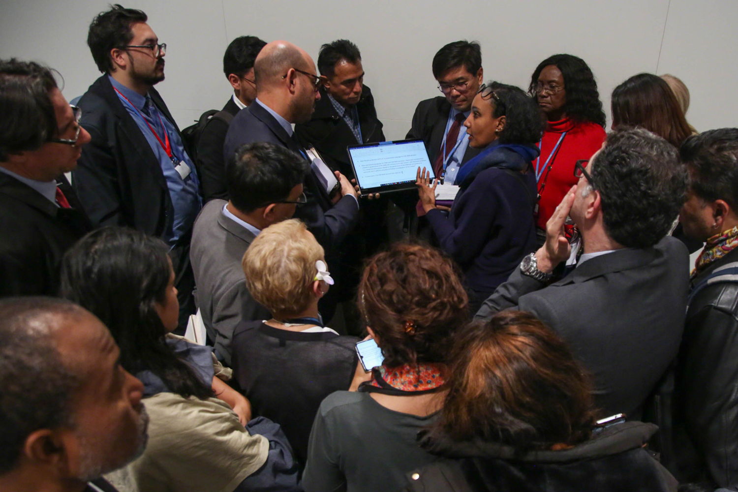 Delegates from Grenada, Malaysia, Brazil, Saint Lucia, and Gabon huddle outside the negotiating rooms, Saturday December 14. Photo by Kiara Worth.