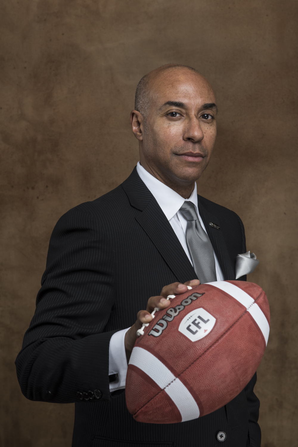 Commissioner Jeffrey L. Orridge with an official game ball displaying the CFL's new logo