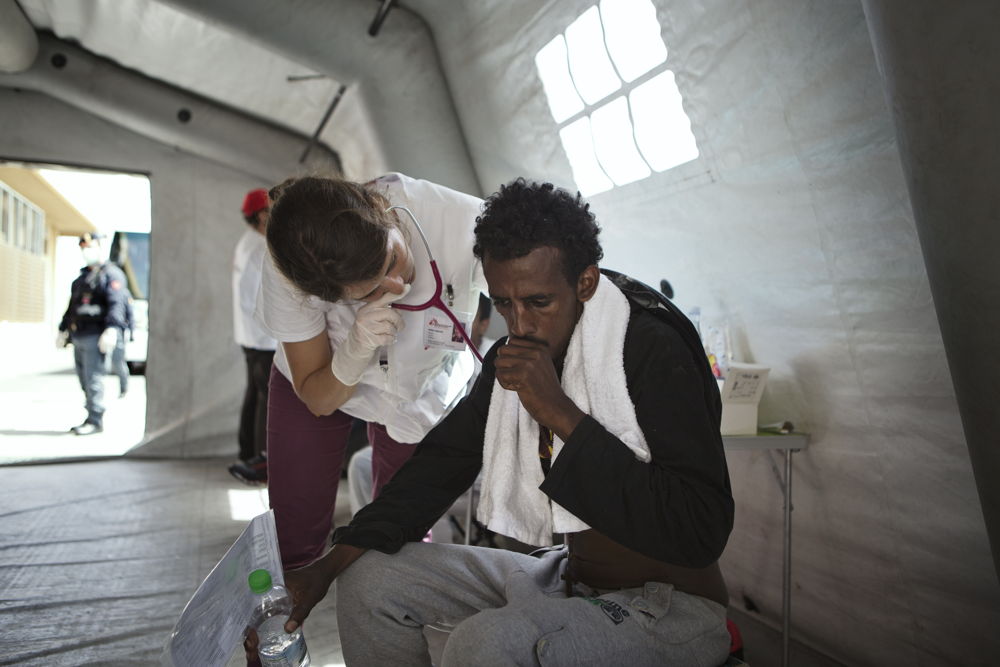 Credit: Alessandro Penso / MSF Caption: 2015. Pozzallo. Italy. Anna, a doctor with MSF, checks the health of an Eritrean man during the arrival of 369 migrants on the search and rescue vessel the M.Y. Phoenix at the port of Pozzallo. Staff from the MSF team working at the CPSA (Centro di primo soccorso ed accoglienza – first reception centre) in Pozzallo provide medical and psychological care to those who have arrived.