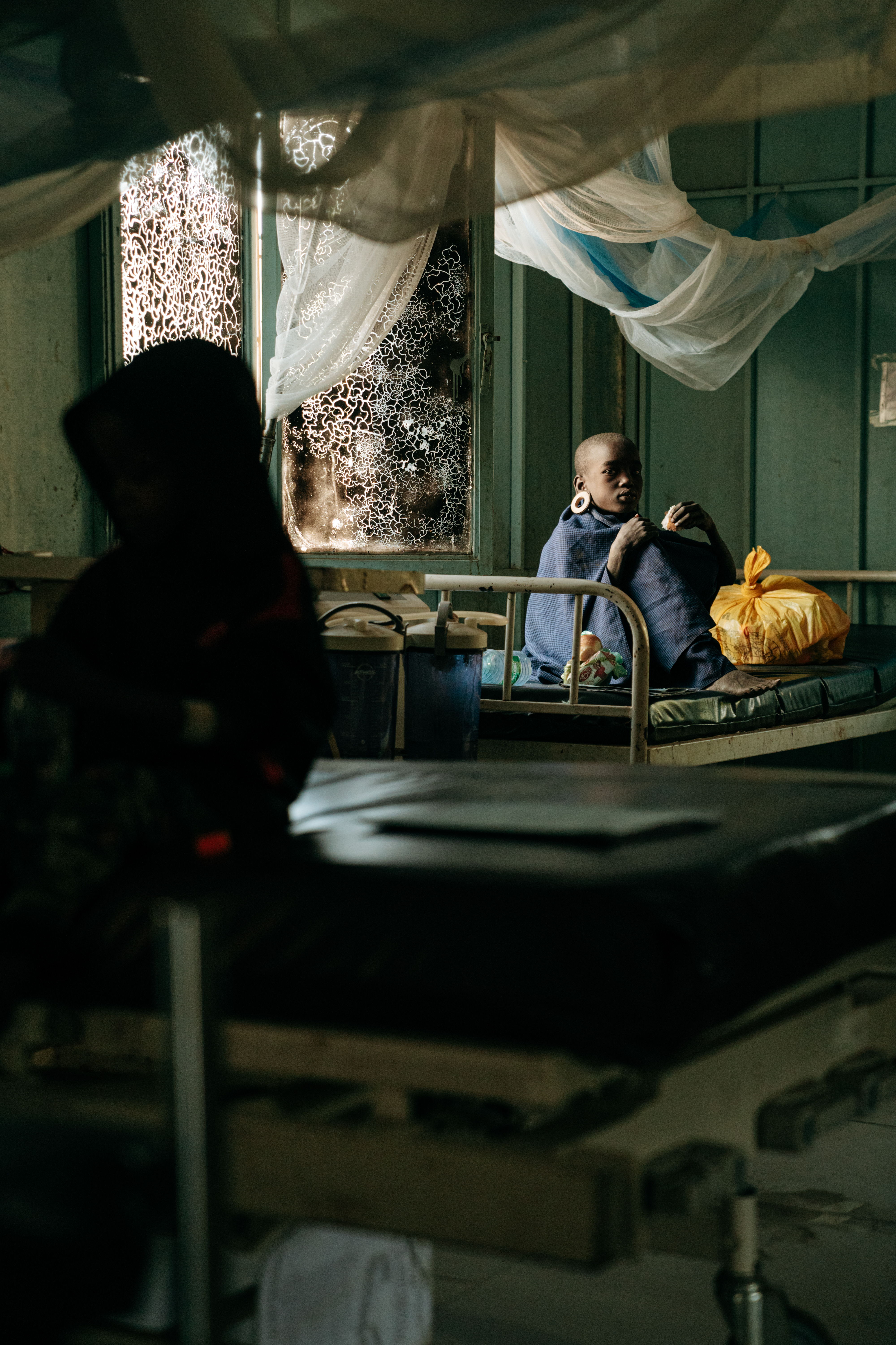 A young Mursi is sitting on her bed waiting for the doctor to check on her. She is suffering from Kala azar but she is getting better.