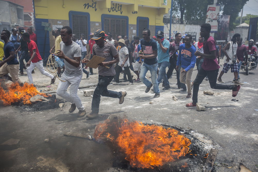 Manifestantes corren cerca de neumáticos en llamas durante una protesta en Puerto Príncipe el 9 de junio de 2019. © Jeanty Junior Augustin/MSF