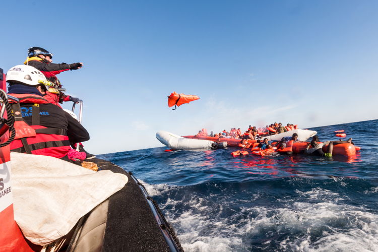 The Aquarius team throw life jackets to people on-board a sinking dinghy before rescue, January 2018. Copyright: Laurin Schmid/SOS MEDITERRANEE 