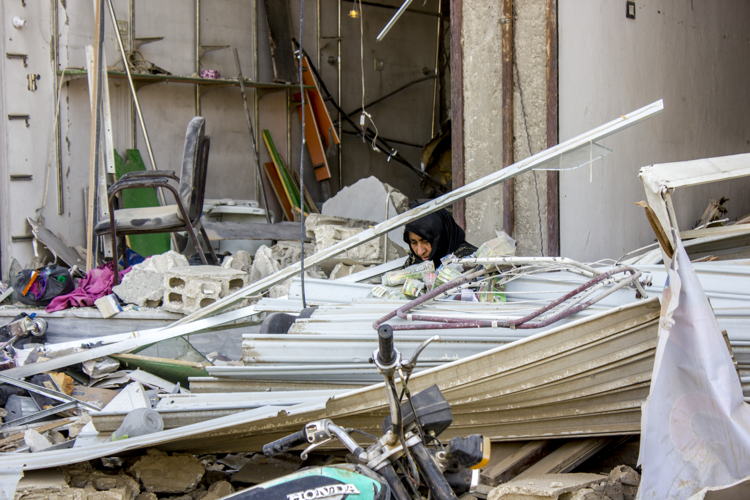 A woman sitting in the middle of what’s left from her house cleaning it and searching for her lost documents. Al Mishlab, east of Raqqa city. Credit: Diala Ghassan/MSF