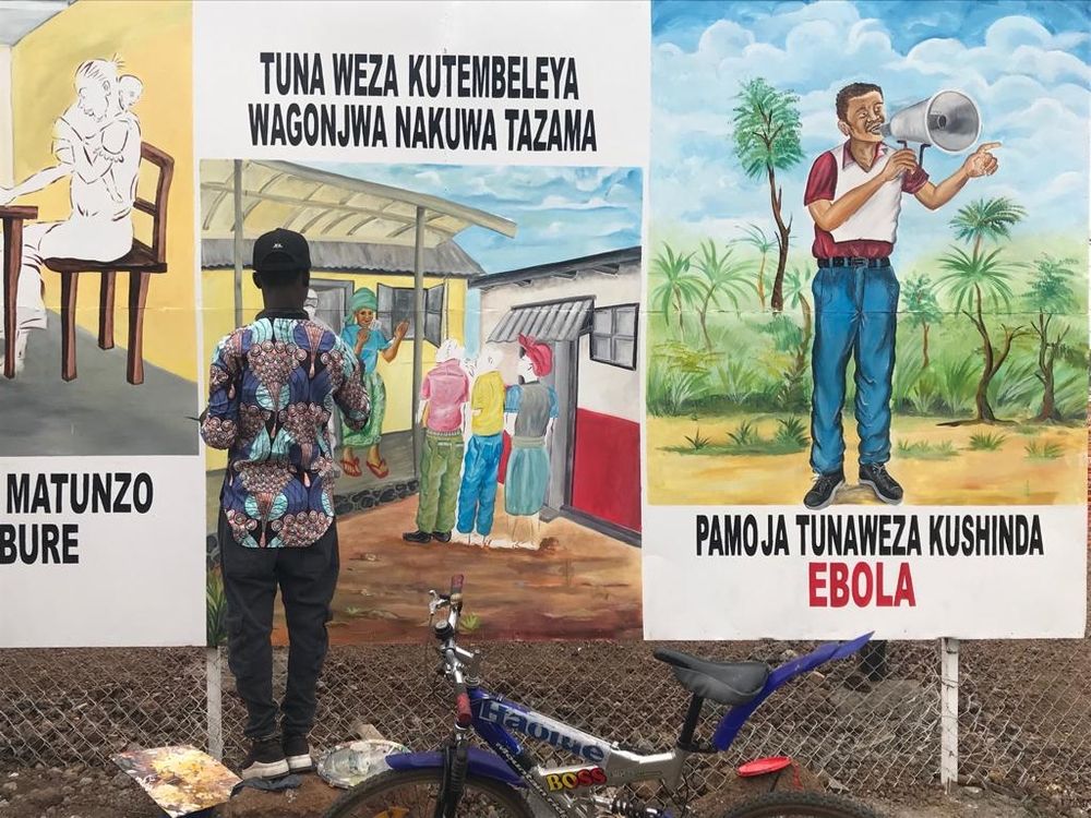 Artistas locales pintan en la valla del nuevo Centro de Tratamiento del Ébola en Munigi, Goma, para ayudar a concienciar sobre la epidemia a las comunidades locales. ​ © Jinane Saad/MSF