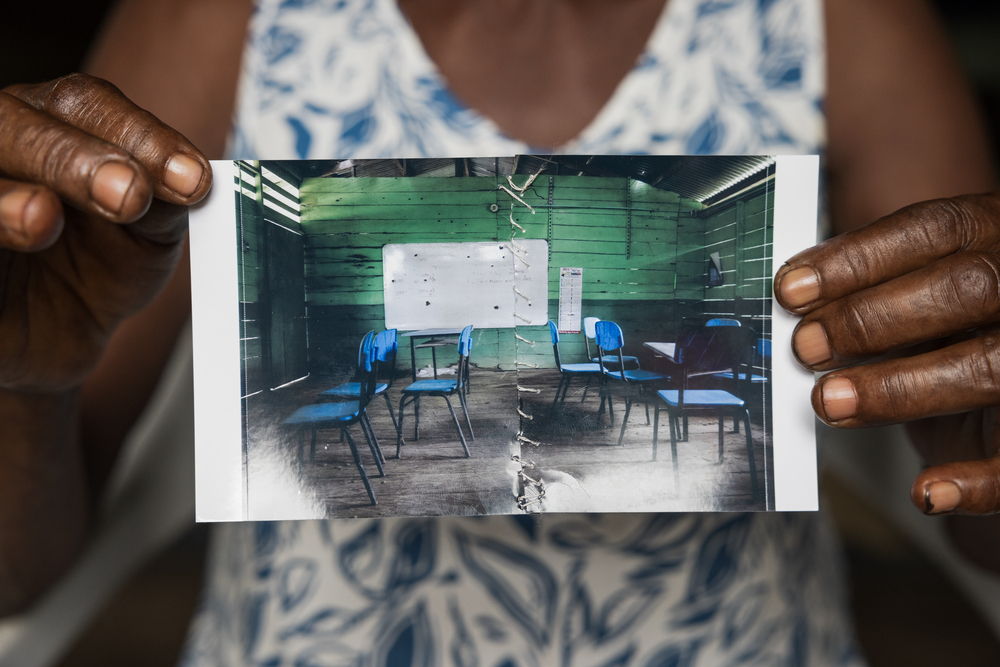 Margarita Rojas Mena, in Mojaudó, stitched up the photograph of the community school, wounded by bullets from an armed confrontation. Mojaudó, Alto Baudó, Chocó.