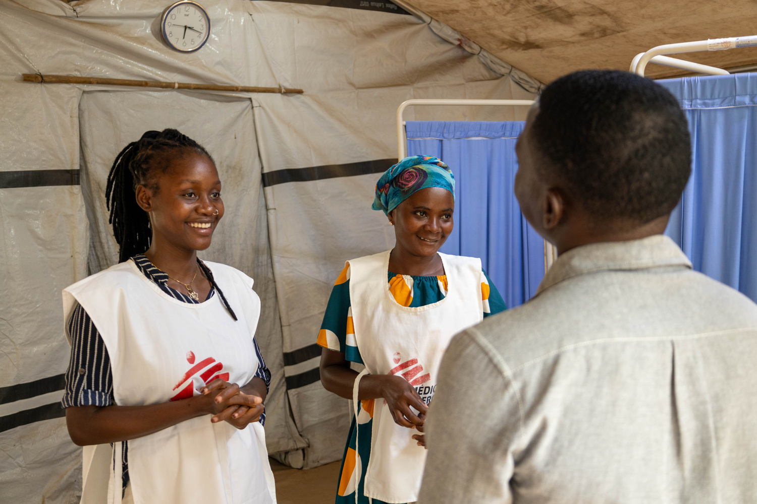 Living with HIV/Aids through Conflict and Displacement - Macomia Fahamo Chabane (name changed) talking with MSF’s nurse Dilénia Adolfo (on the left) and health promoter Verónica Leonardo (on the right) at MSF’s clinic in Nanga, Macomia district, Cabo Delgado.  In September 2023, Fahamo, was received by these two MSF staff when he was admitted in critical conditions and found out he had HIV.  Fahamo is 24 years old and was displaced multiple times over the past years due to violence and conflict between non-state armed groups and government allied forces in Cabo Delgado. Since Fahamo found out he had HIV, he returns every month to MSF’s clinic to receive ART and monitor his health condition. Photographer: Martim Gray Pereira