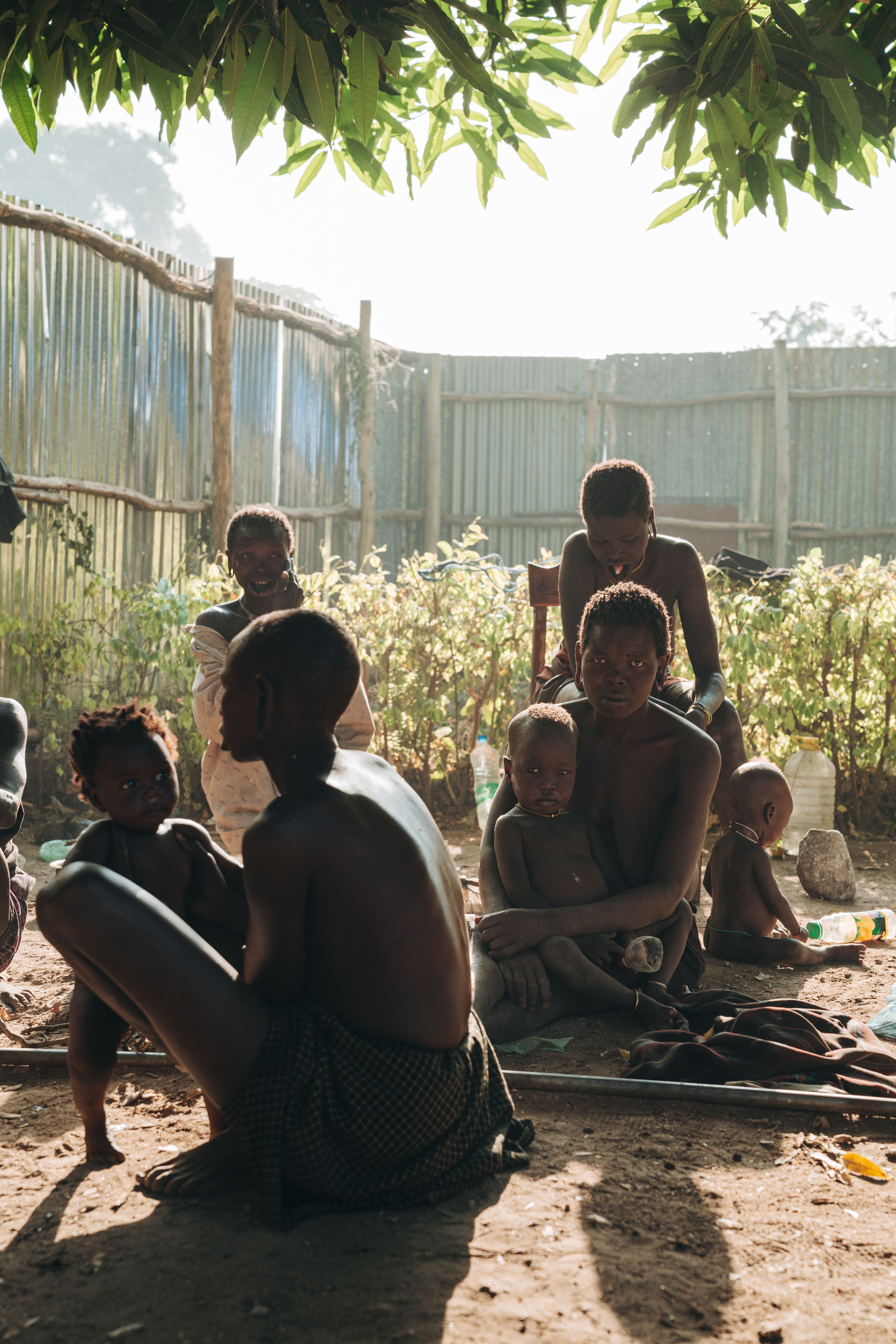 Mursi tribe at Jinka hospital. Parents and caretakers with children outside of the ward. They cook foods they prefer on wood fires.