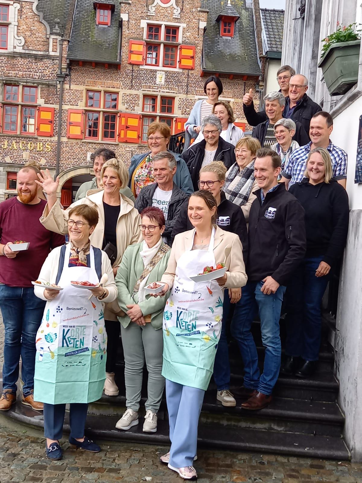 persmoment Lokeren met gedeputeerde Grillaert (vooraan rechts), schepenen lokaal bestuur Lokeren Nina Van der Sypt (vooraan links) en Marjoleine De Ridder (bovenaan links), omringd door Lokerse producenten