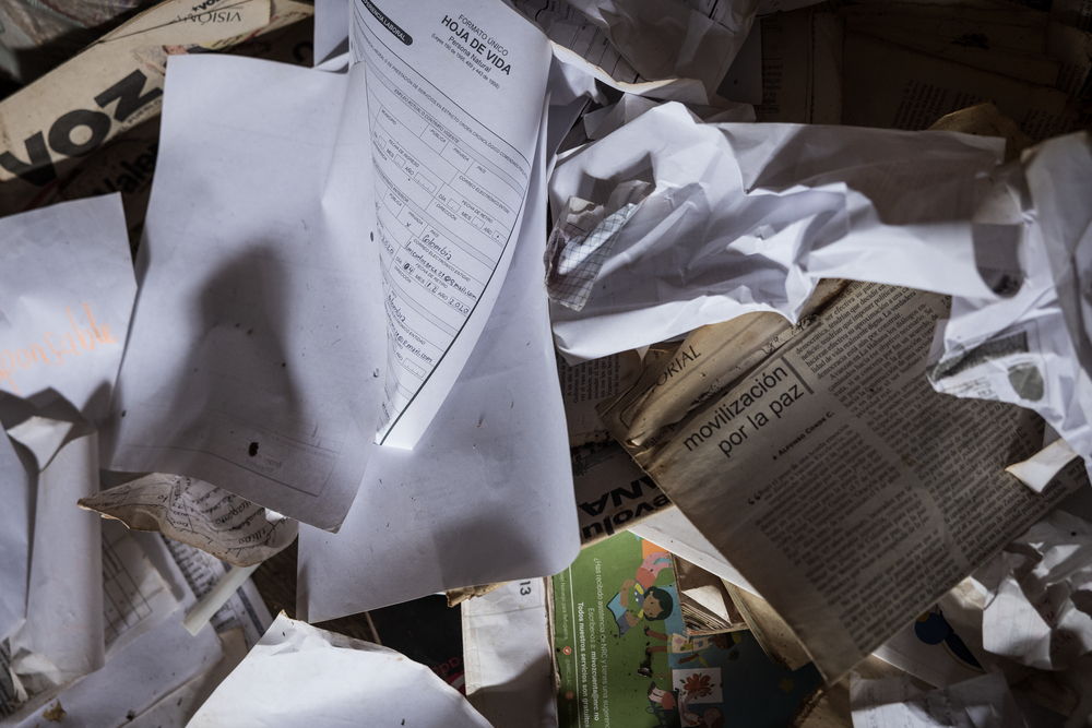 Photograph in the room of the husband of Nancy Arce, a murdered Indigenous guard. The fragments of paper on the floor are the last traces of his presence in this space. Indigenous community of Puesto Indio, Alto Baudó, Chocó.