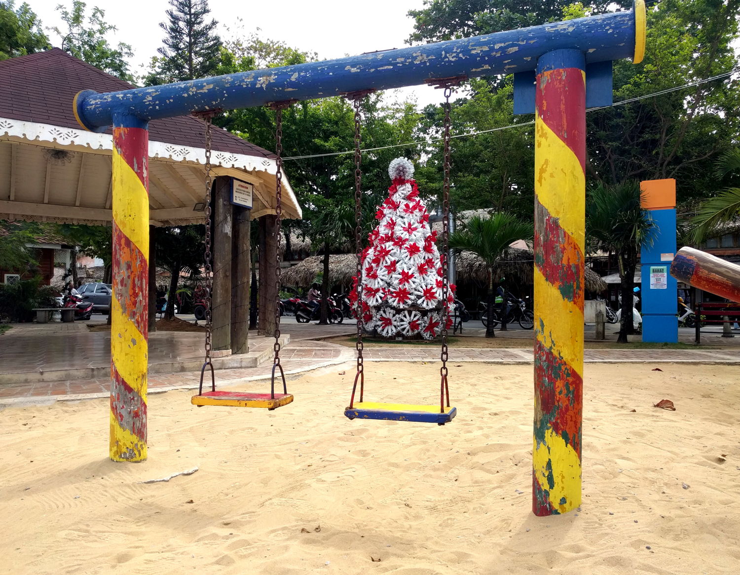 A Christmas tree made with plastic bottles, behind a swingset