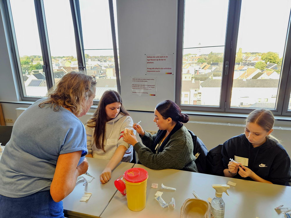 leerlingen van VLOT! Campus Sint-Lodewijk Lokeren leren prikken tijdens de workshop basisverpleegkunde van IVV Sint-Vincentius Gent bij VITAZ Lokeren