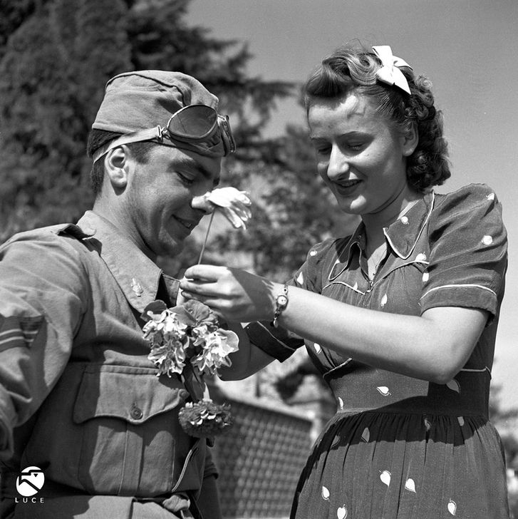 Woman giving flowers to a member of the GIL battalion after the battalion arrived in Valenza, Piedmont, Italy.  Photograph, 1940, by Istituto Nazionale Luce. AKG4566011 © akg-images / FAF Toscana - Fondazione Alinari per la Fotografia