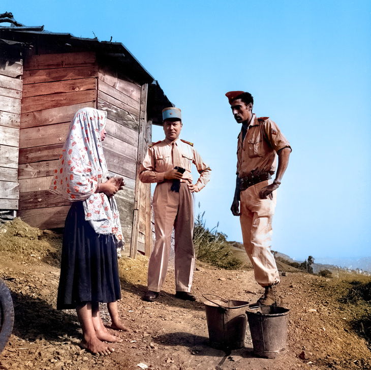 AKG9242343 Deux membres des S.A.S. (Sections Administratives Spécialisées) : un officier avec le "képi-bleu" (représentant du sous-préfet) et un "moghazni" (contractuel algérien) discutent avec une femme algérienne dans une zone rurale en 1957