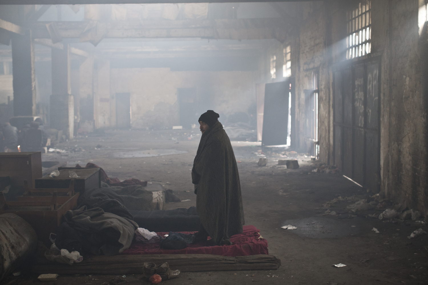 Een man staat in een oud treinstation in Belgrado waar vluchtelingen verblijven © Marko Drobnjakovic