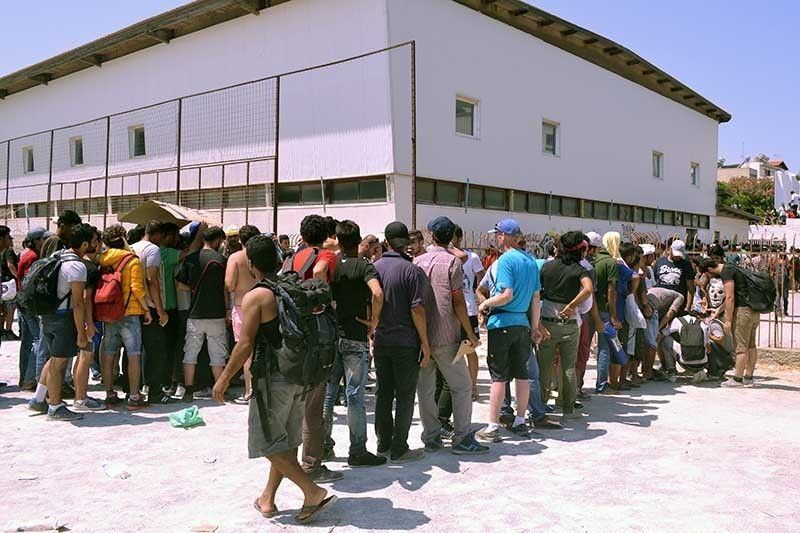 Migranten vormen wachtrijen aan het gemeentelijk stadion en wachten op registratie door de Griekse politie