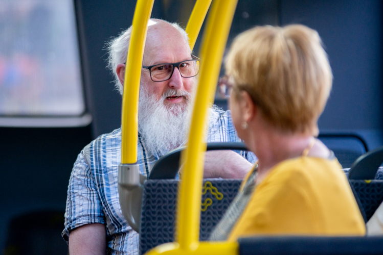 Een oudere reiziger zit in de bus