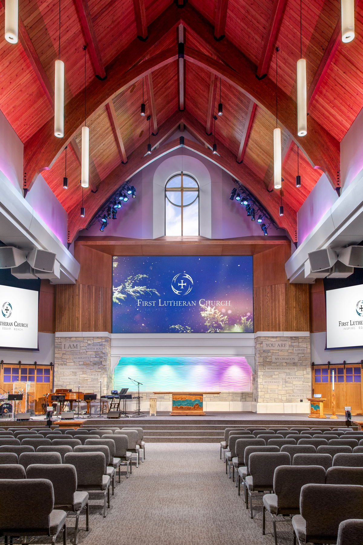 First Lutheran Church Celebration Center stage with giant (non-motorized) Da-Lite Cinema Contour HD Progressive 282” x 162” screen and motorized left & right side 192” X 108” Da-Lite screens