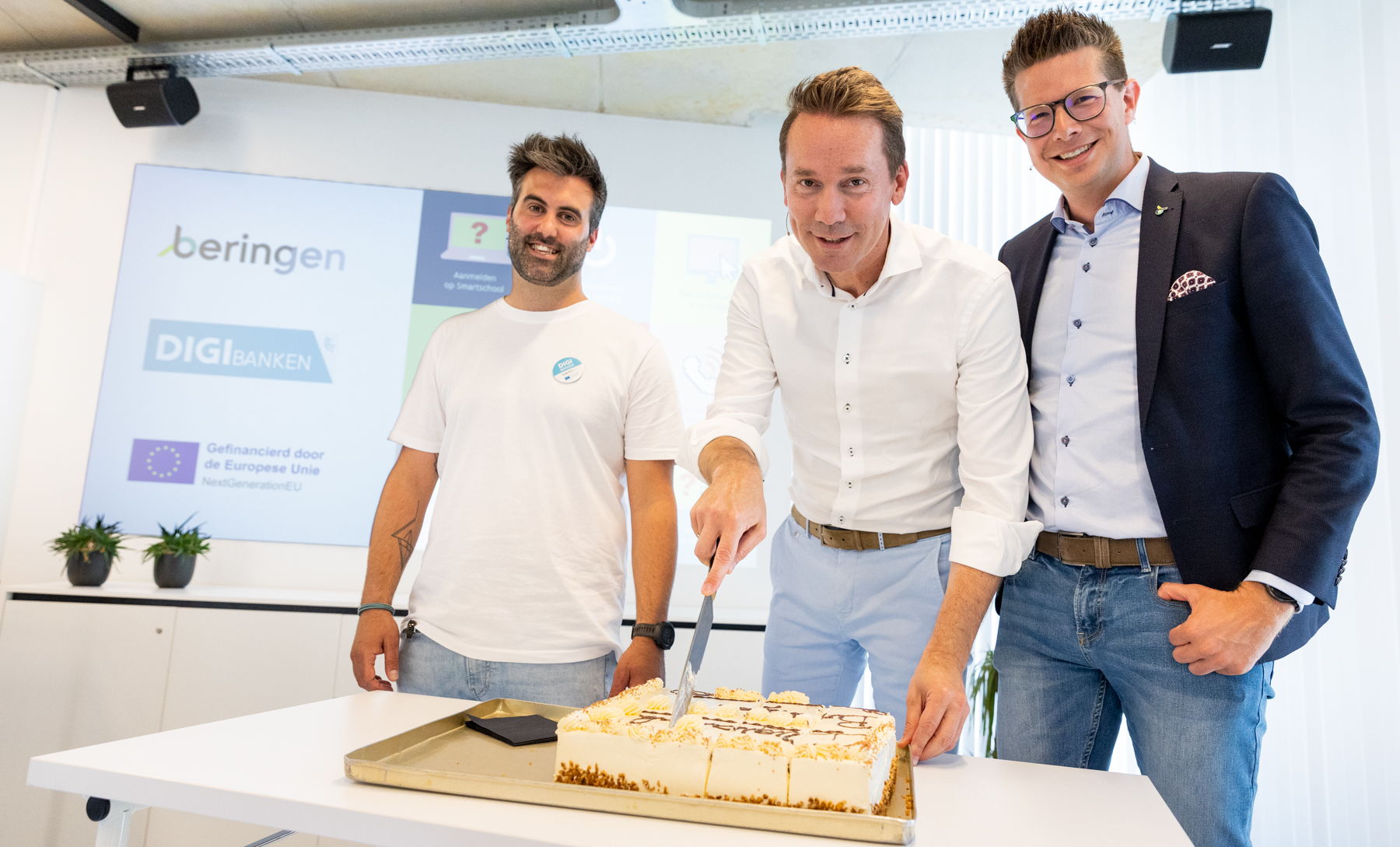 Thomas Lemmens, Jo Brouns en Thomas Vints snijden de taart aan naar aanleiding van de officiële opening van de digibank van Beringen.