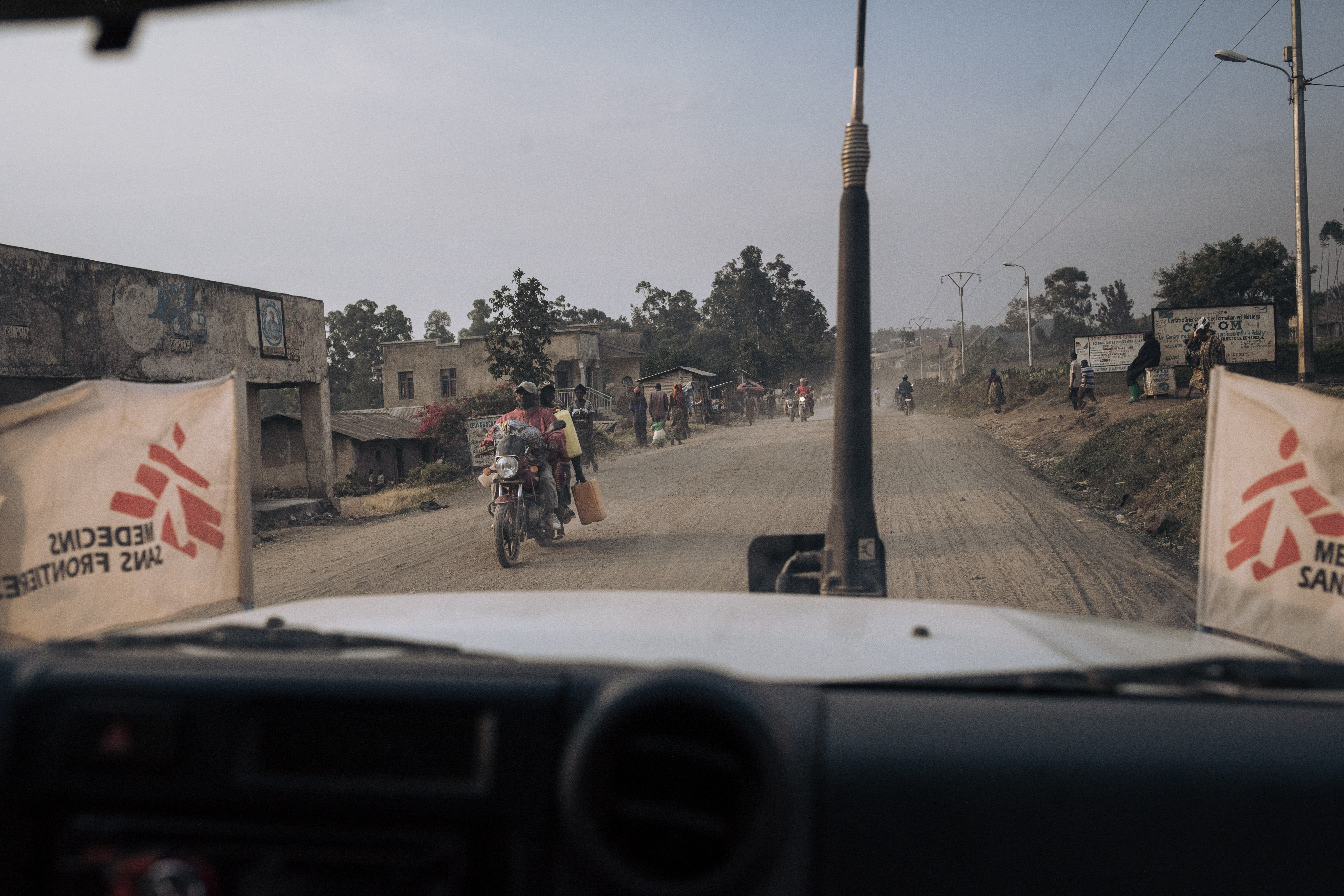 An MSF vehicle passes moto-taxi drivers on the main road outside Rutshuru Centre on July 14, 2022, in North Kivu province, eastern Democratic Republic of Congo.