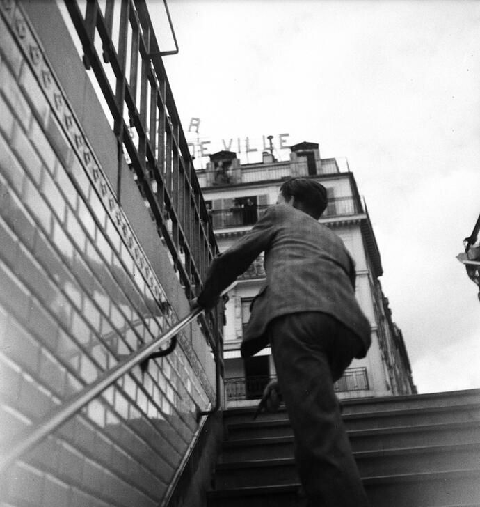 AKG10620265 Un jeune homme armé d'un pistolet guette ce qui se passe devant l'Hôtel de Ville, en s'abritant dans la bouche du métro située directement sur la Place de l'Hôtel de Ville. Photo, août 1944 © René Zuber / akg-images
