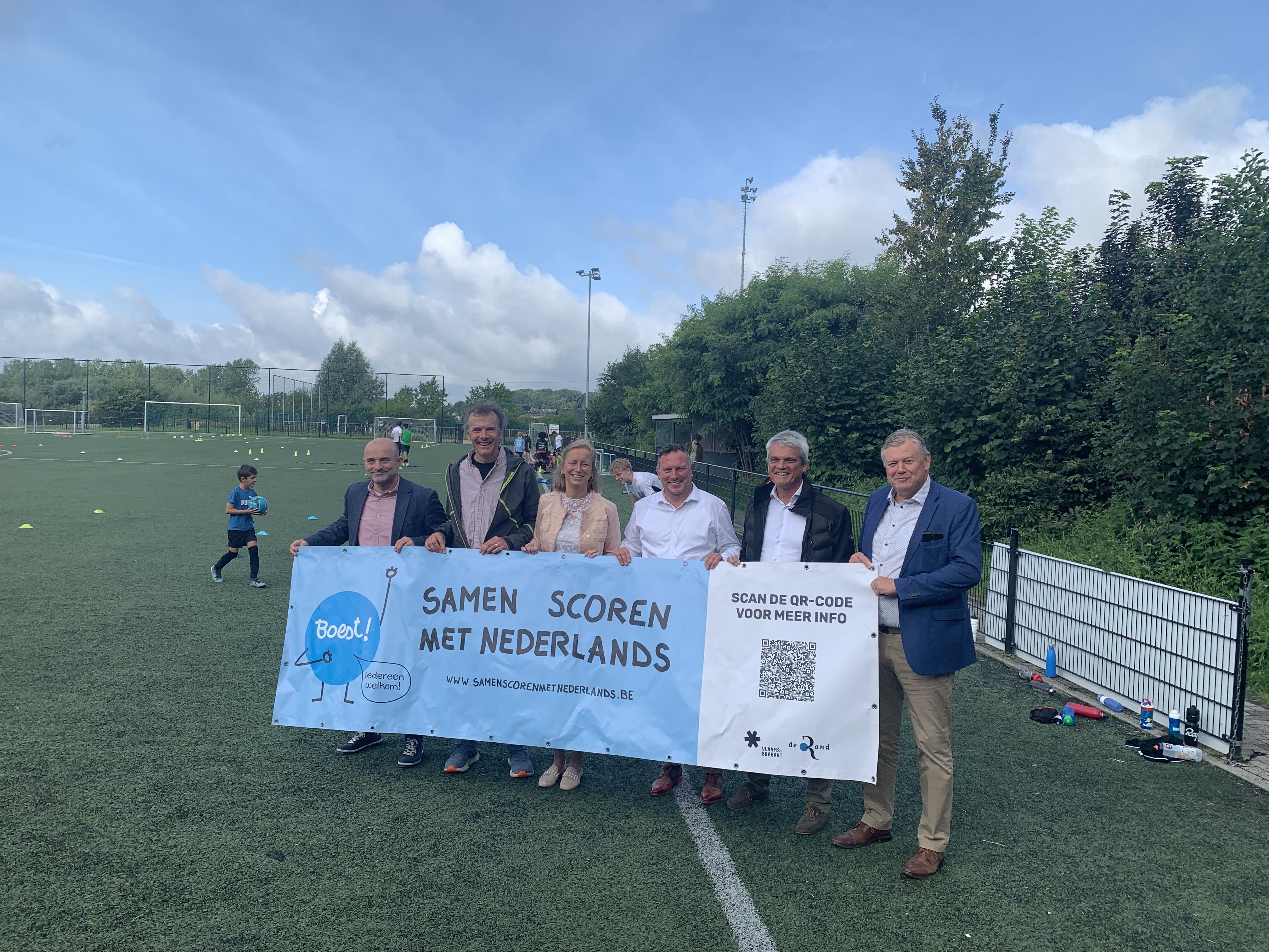 Op 9 augustus overhandigde gedeputeerde Gunther Coppens de eerste 'Samen scoren met Nederlands'-spandoek aan het gemeentebestuur van Asse op het voetbalveld van FC Asse 2002.