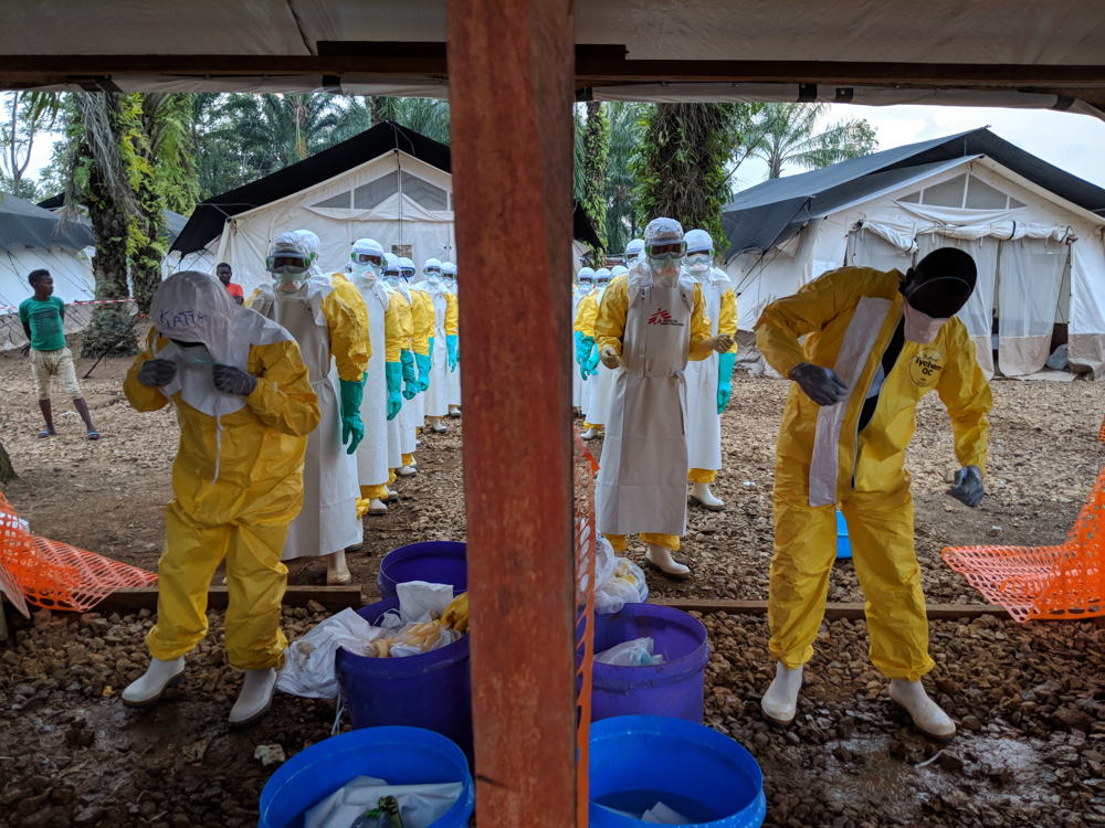 A team that has just finished setting up a tent in the high-risk zone in the Ebola treatment centre, getting out of their personal protective equipment (PPE). It’s hard work, and harder still in such attire. Photographer: Karin Huster/MSF