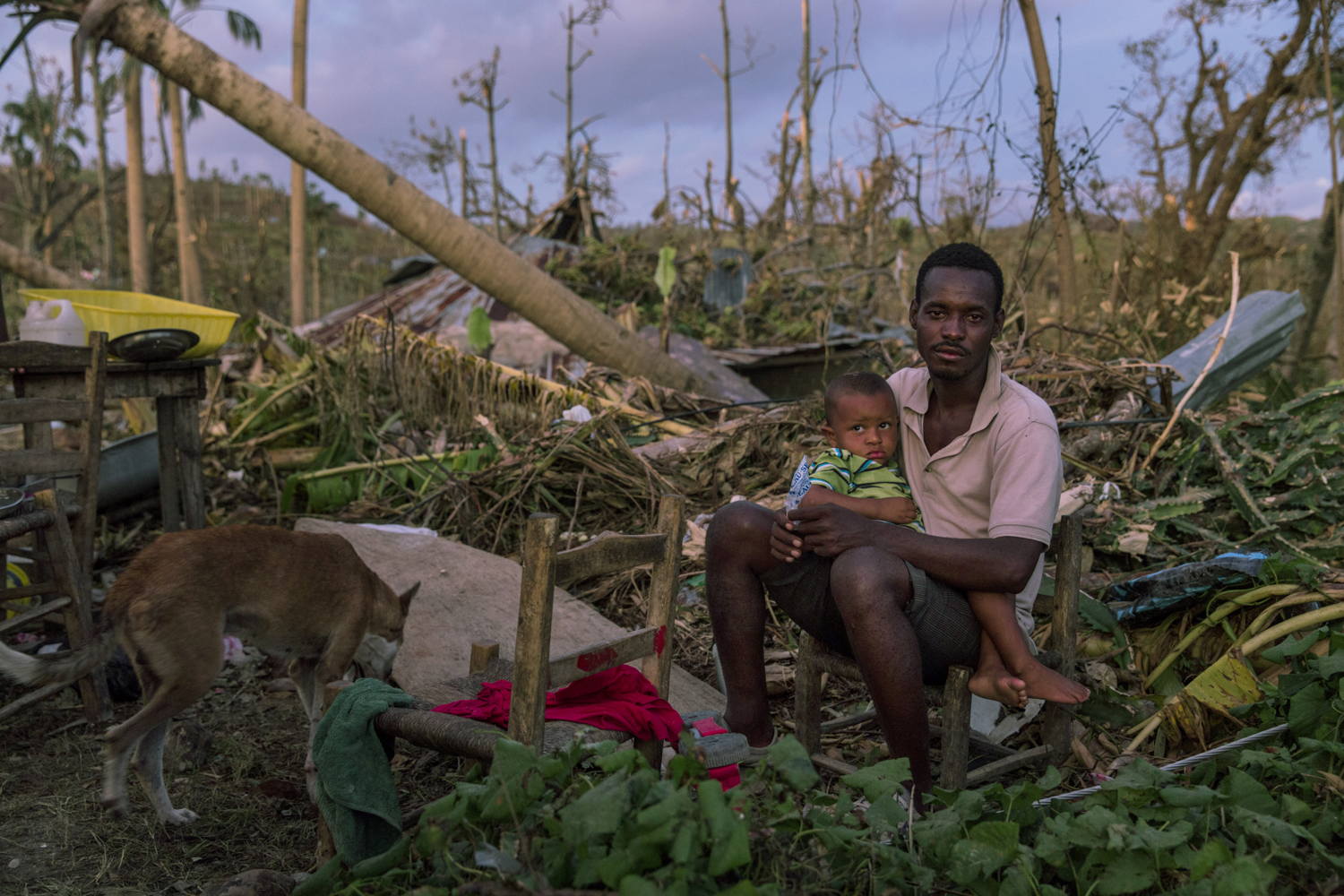 Een man zit met zijn zoon in een verwoest gebied in Port Salut, zuidwest Haiti, na de doortocht van orkaan Matthew op 4 oktober © Andrew McConnell/Panos Pictures