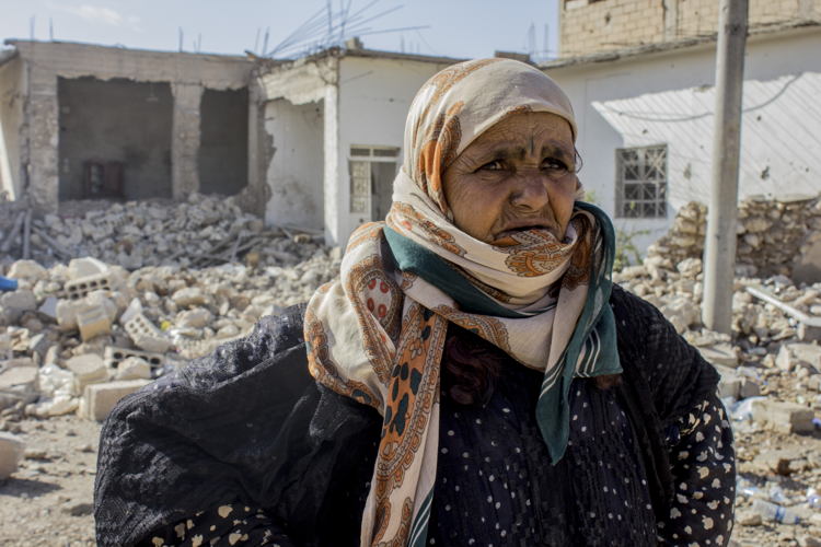 Amneh fled Al Mishlab, east of Raqqa city, with her family eight months ago. They moved five times before coming back as the front lines kept getting closer to their location. They came back to Al Mishlab to find that most of their houses have been destroyed. She is standing in front of her grandchild’s house that was fully destroyed. She said "we will try to rebuild our houses but there is still no services in the area yet." Credit: Diala Ghassan/MSF