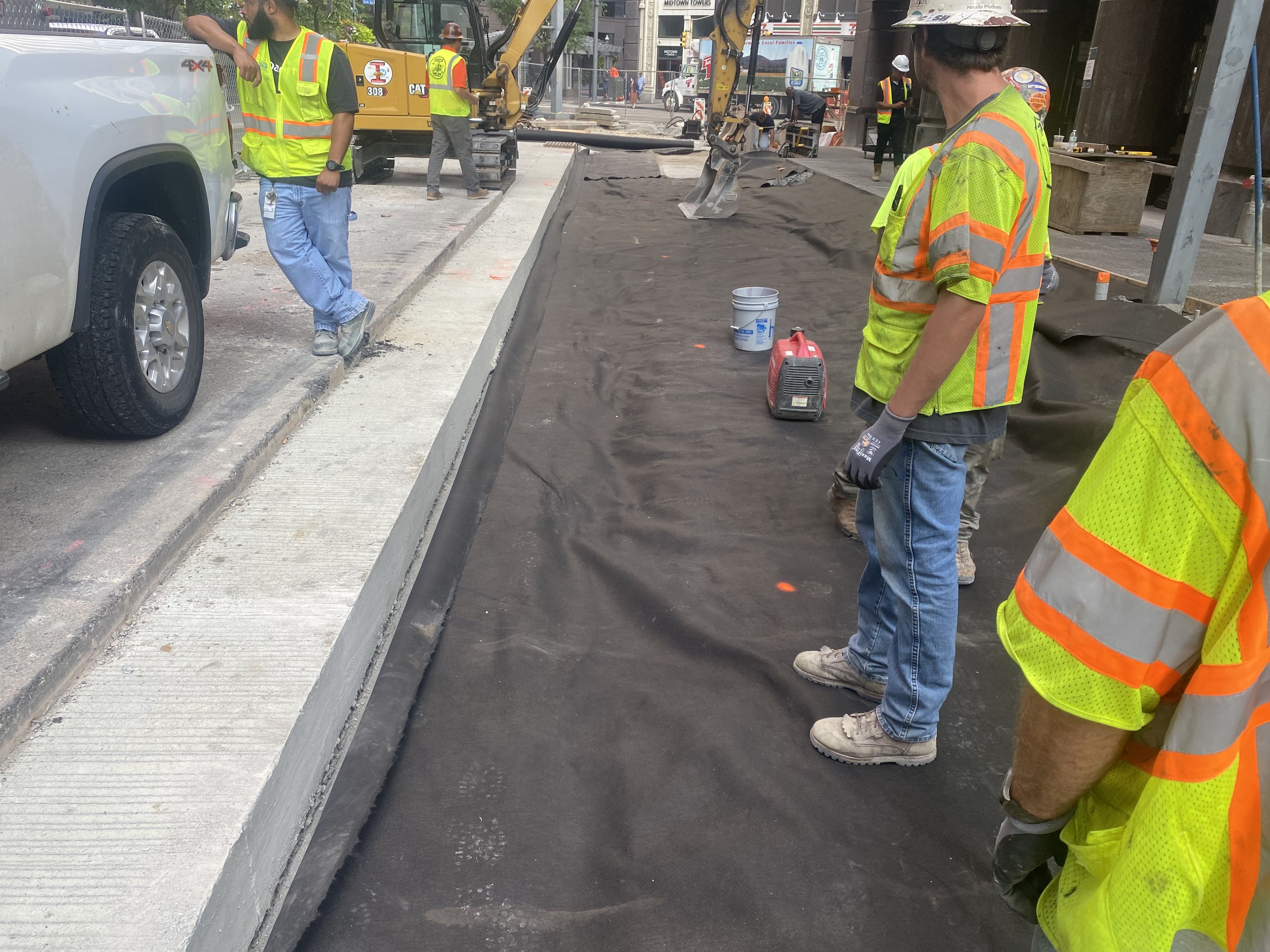 A geotextile material is covering the ground before a concrete footer is poured to support the new granite curb