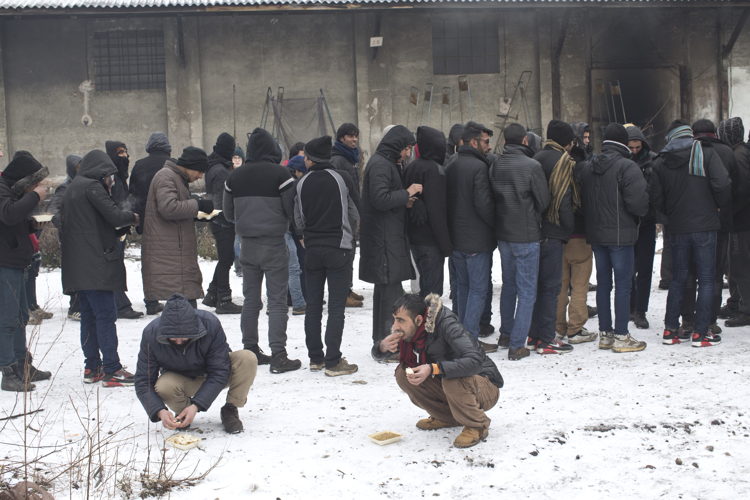 Vluchtelingen wachten op voedsel in een oud magazijn in Belgrado © Marko Drobnjakovic