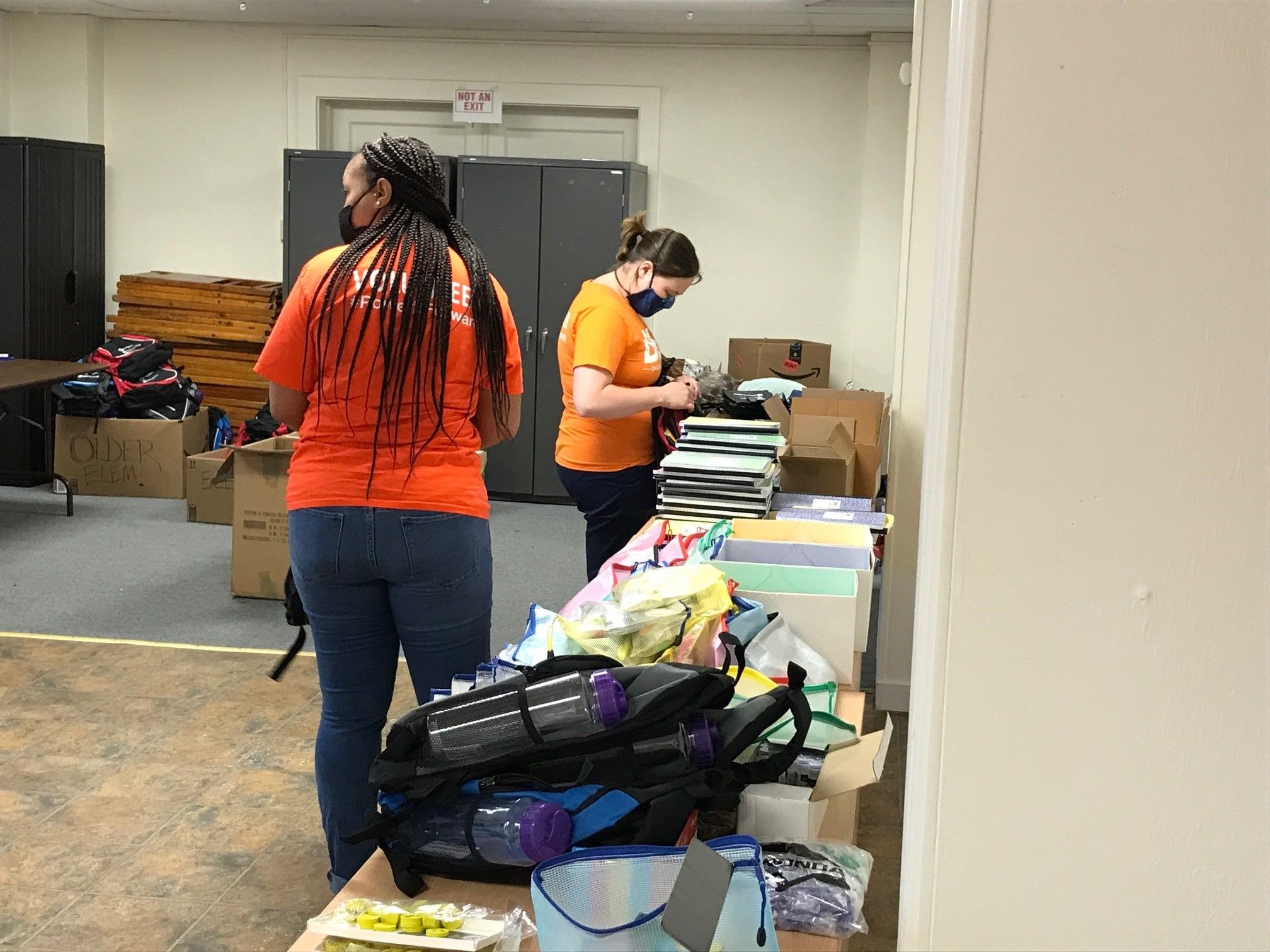 DLC volunteers Jenna DeLozier (right) and Amber Watson help fill backpacks with supplies for Hosanna House's back-to-school giveaway.