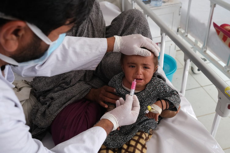 A medic gives glucose to a patient in the measles isolation ward at Boost hospital. Over 440 measles patients were admitted to the ward in January and February 2022. 
