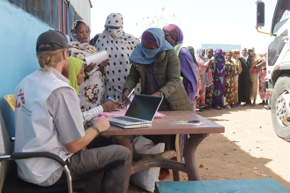 MSF is providing food to patients enrolled in its programmes and their families. Given the dire malnutrition situation demand for MSF’s food distribution programme far outweighs our capacity. Sadly this means we have to turn people away. Here an MSF staff member checks people are registered in our programmes before giving them a voucher to receive their food basket | Date taken: 05/01/2025 | Photographer: Abdoalsalam Abdallah | Location: Sudan