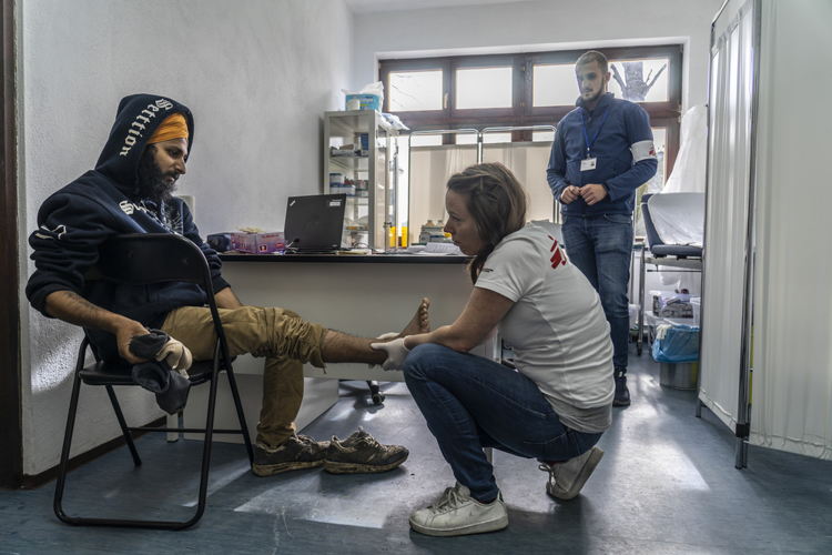Een consultatie door Artsen Zonder Grenzen op 2 km van het kamp in Vucjak. Deze man met stapproblemen, wordt verzorgd © Anna Pantelia/AZG.