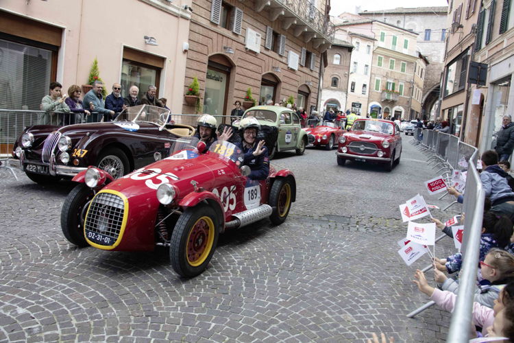 Día de asueto para la Mille Miglia: jóvenes que animan mientras los vehículos pasan por la ciudad. 