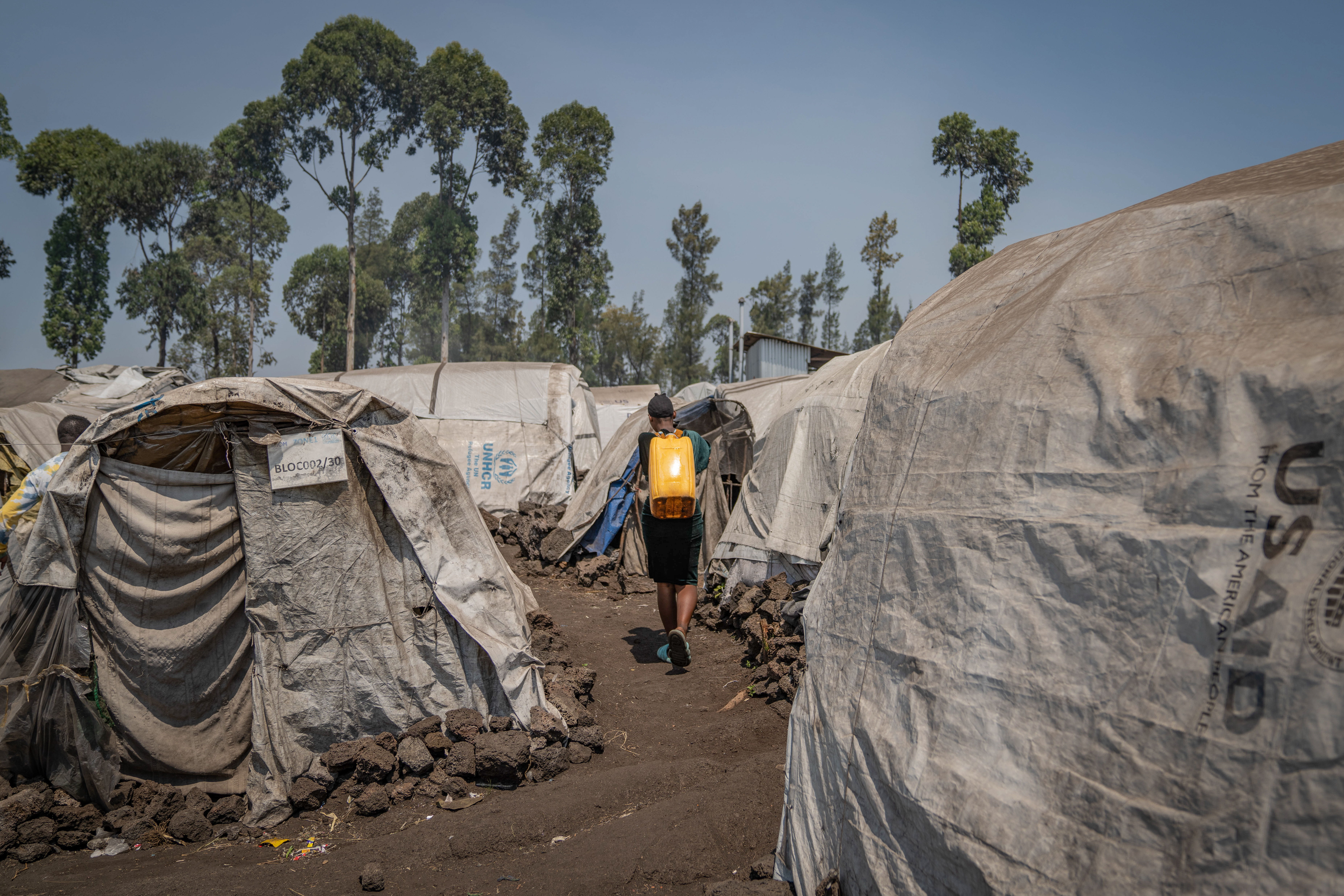 Una mujer desplazada transporta agua entre las tiendas del campo de Elohim, en los alrededores de Goma (República Democrática del Congo). © Moses Sawasawa.