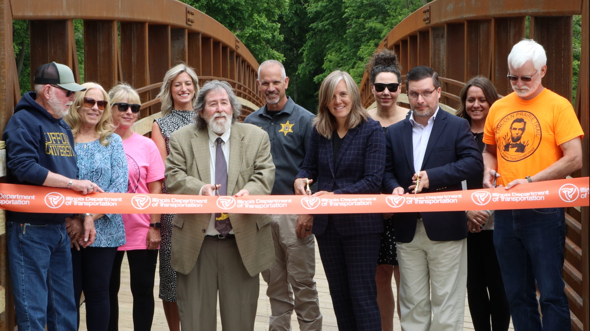From Left to right: City of Taylorville Alderman Steve Dennis; Acting Illinois Transportation Secretary Gia Biagi; Pana Mayor Nathan Pastor; and Terry Baker, Lincoln Prairie Trails Conservancy, cut the ribbon on the new Lincoln Prairie Trail Bridge in Taylorville, IL. From Left to right: City of Taylorville Alderman Steve Dennis; Acting Illinois Transportation Secretary Gia Biagi; Pana Mayor Nathan Pastor; and Terry Baker, Lincoln Prairie Trails Conservancy, cut the ribbon on the new Lincoln Prairie Trail Bridge in Taylorville, IL.