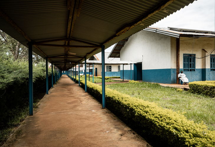 A nurse sits outside on the deserted surroundings, with no patients at the Drodro reference hospital in Ituri, DRC. Photographer: Michel Lunanga |Location: Ituri province | Date: 17/05/2023