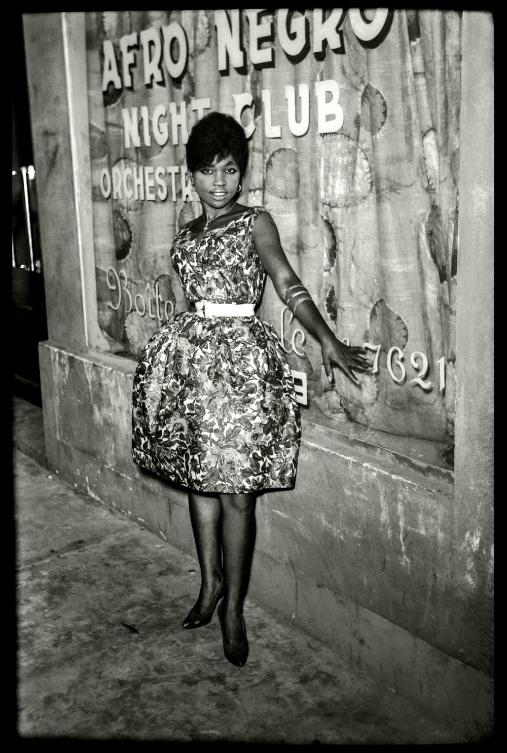 Jean Depara, Une belle Kinoise ceinturée dans sa robe tulipe devant l’Afro-Négro Club, orchestre City-Five, 1960 © Estate DEPARA, courtesy of Magnin-A Gallery 
